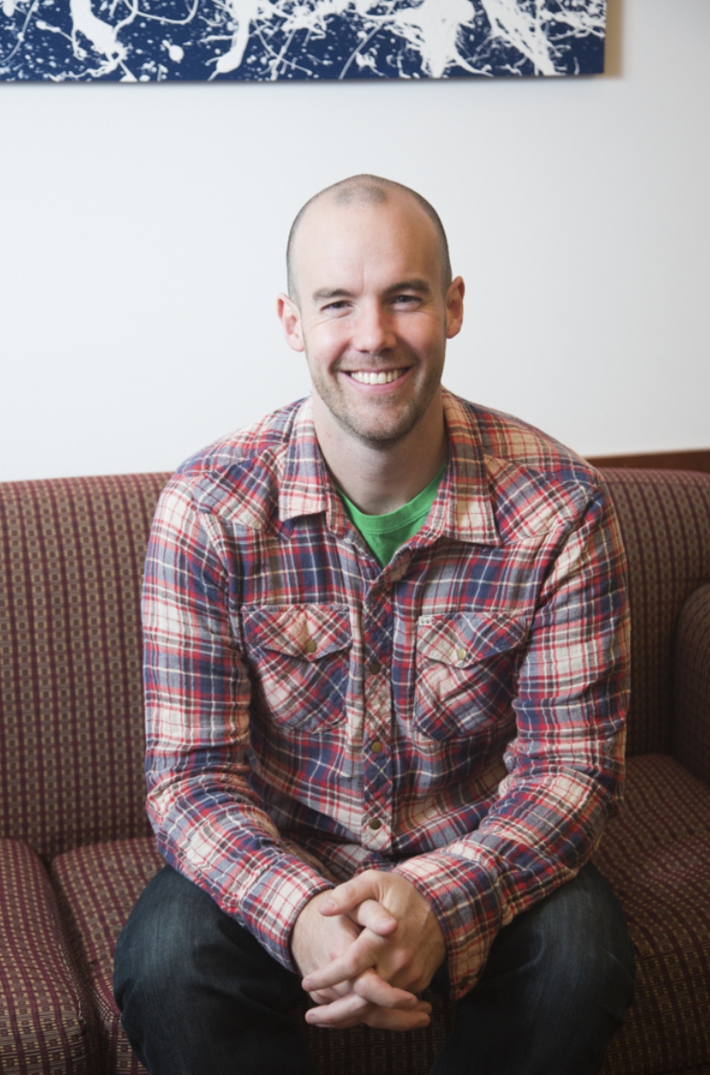 behavior scientist  wearing a flannel shirt sitting on a couch
